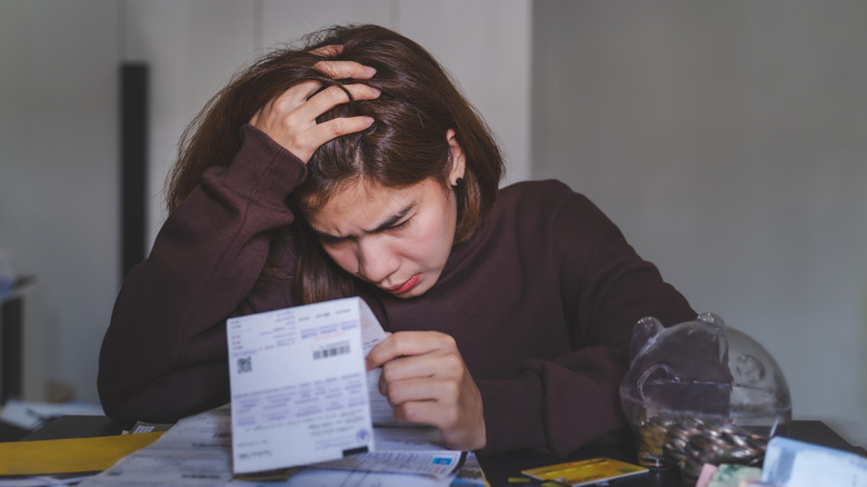 A young woman looks stressed as she goes over her finances