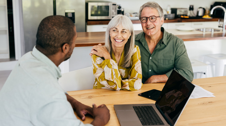 A happy retired couple meeting with a financial planner in their home.