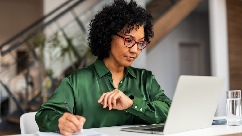 A middle-aged woman working at on a laptop in an office
