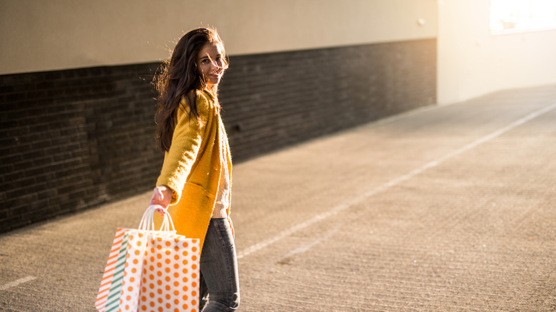 young person carrying a shopping bag in sunlight