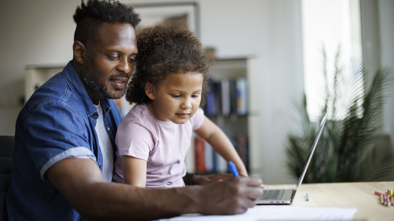 Man working from home and taking care of his daughter