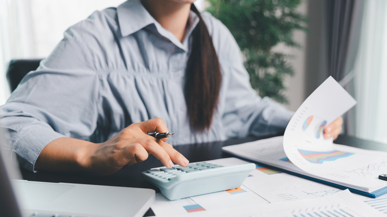 Woman looking at paperwork and using a calculator