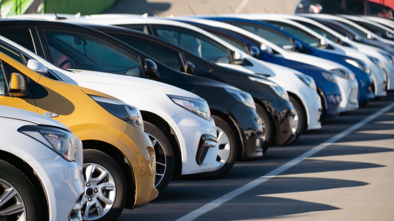 Niz bijelih, crnih, zlatnih i plavih automobila