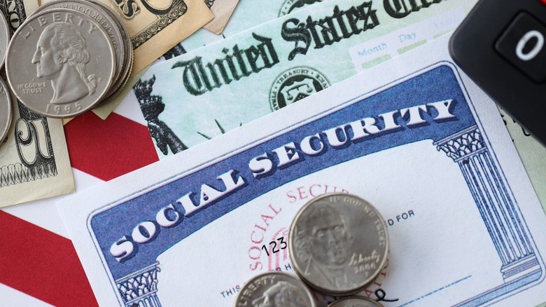Coins stacked on a Social Security card with a U.S. Treasury check and other money in the background.