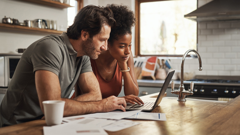 multiracial couple looking at laptop and paperwork