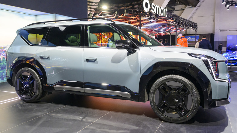 A white Kia EV9 parked indoors at a car show.