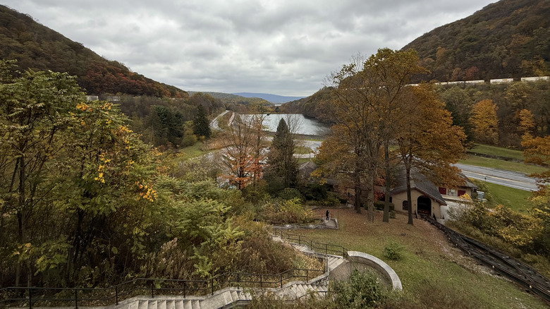 An Altoona, Pennsylvania, valley featuring a railroad, a river, a small house, and a thick tree line on either side.