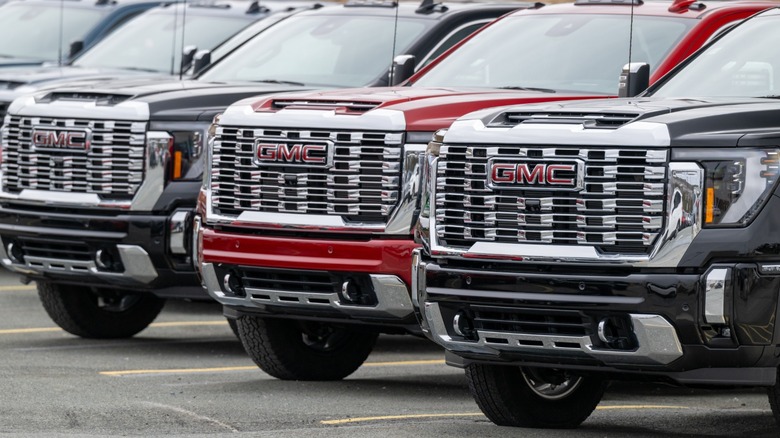 A row of new GMC pickup trucks lined up on a lot.