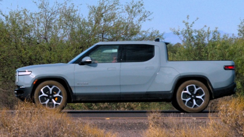 Side view of a light blue truck on the road.