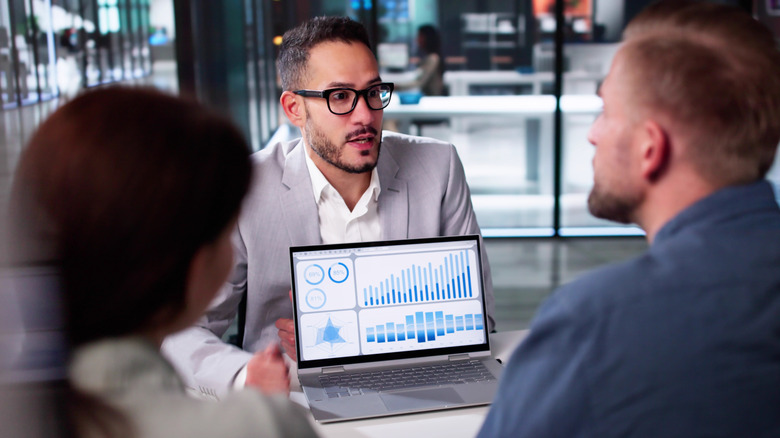 Man in glasses showing two people figures on a laptop