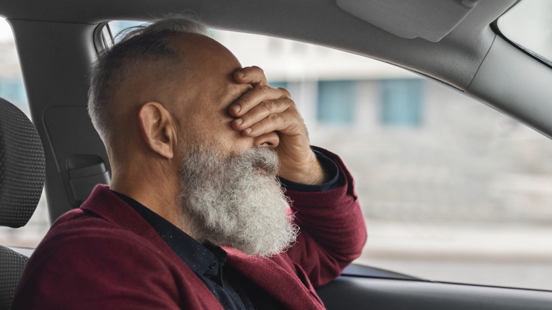 An older man looks frustrated while driving