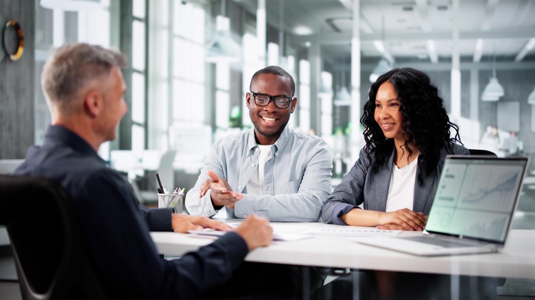 A private wealth manager advises a couple in an office.