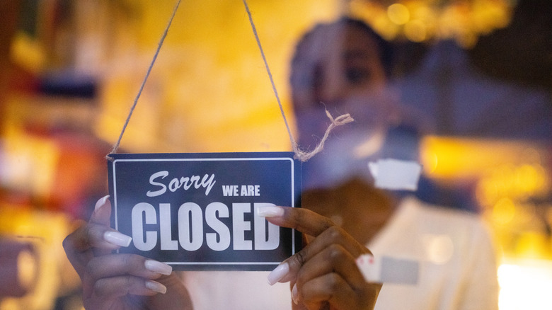 Person hanging a closed sign in a window