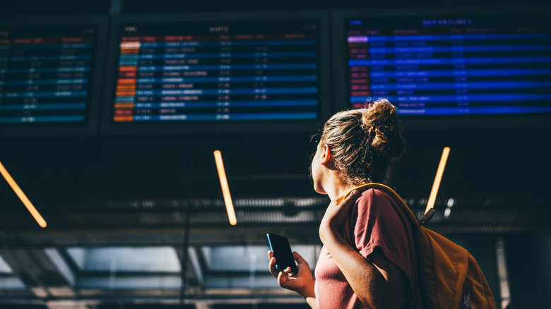 Woman looking at airport schedule boards
