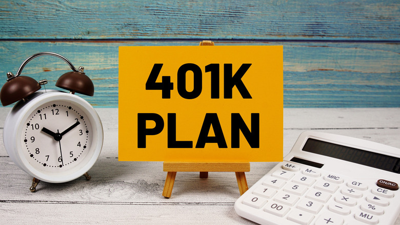 A sign for a 401k plan alongside a calculator and alarm clock