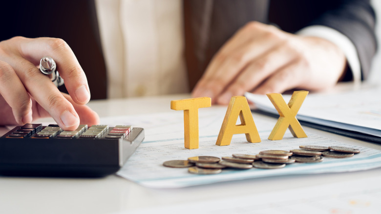 A person using a calculator, perhaps to determine tax obligation