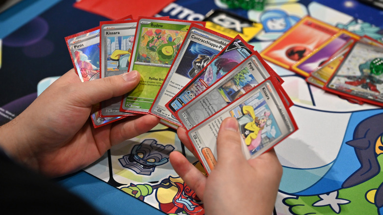 Hands holding a collection of Pokemon cards