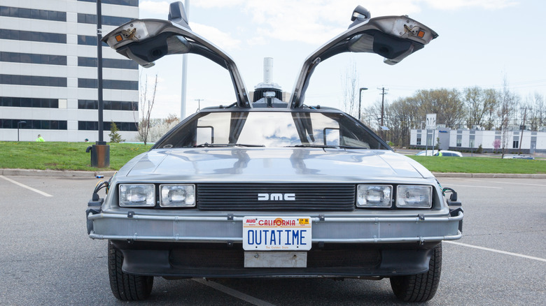 A Delorean with open gullwings, styled to look like the car from Back to the Future, sits in a parking lot, bearing an 