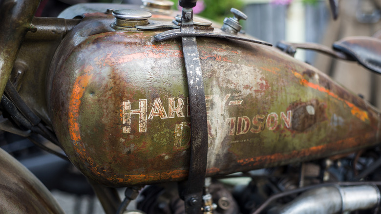 closeup of rusty motorcycle tank with faded harley davidson logo