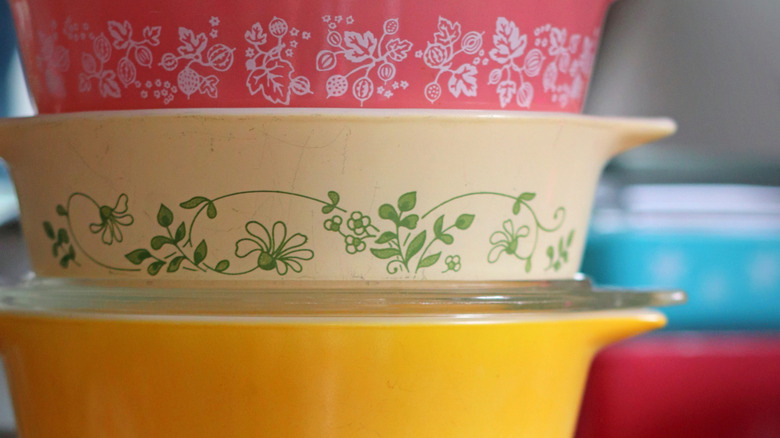 A stack of vintage Pyrex dishes in multiple colors and prints