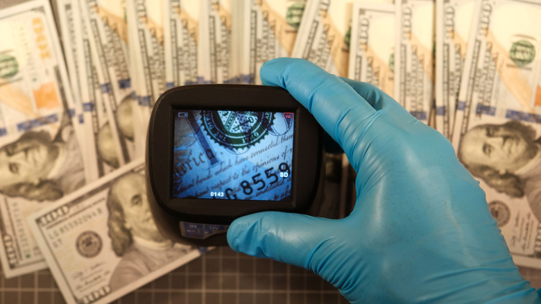 Gloved hand of someone trying to detect fake bills