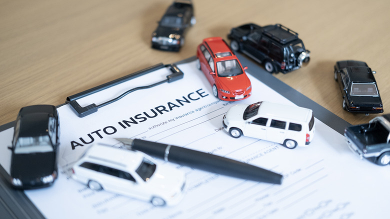Car insurance form covered by toy cars and a pen