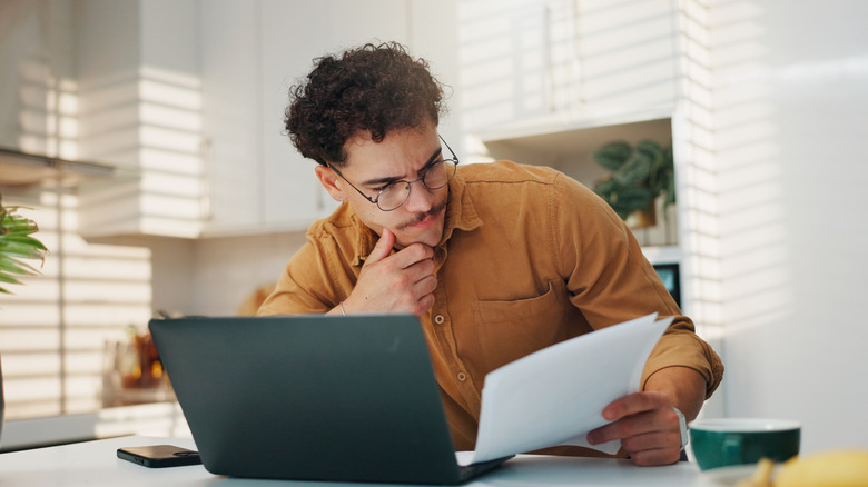 Man with laptop reading bill