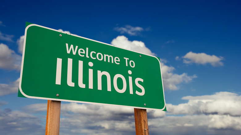 Green welcome to Illinois sign with blue sky behind it