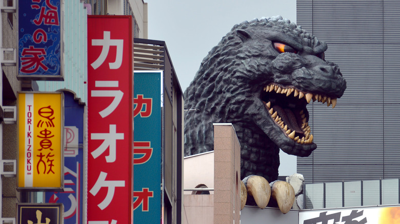 Godzilla's head peeking out from street signs in Japanese