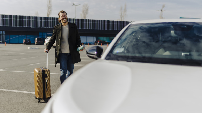 man walking to rental car at airport