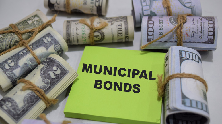 municipal bond on post-it note near rolls of bills
