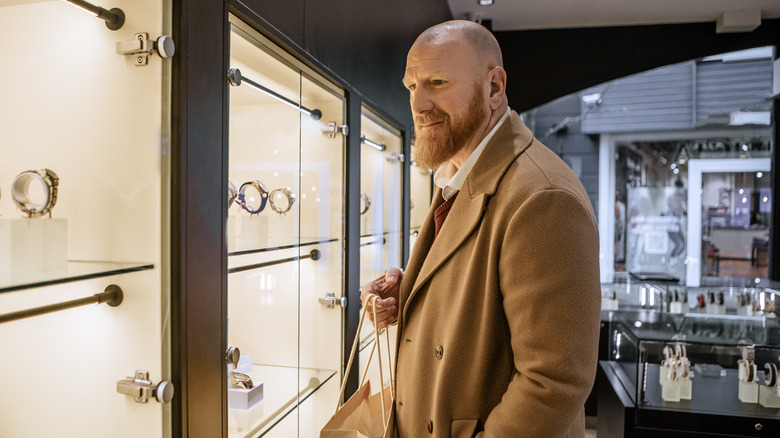 A middle aged man looking at jewelry in a high end boutique.