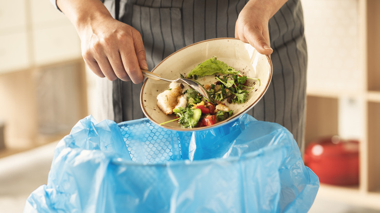throwing out food waste with blue garbage bag