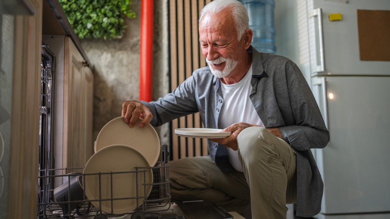 senior man loading the dishwasher