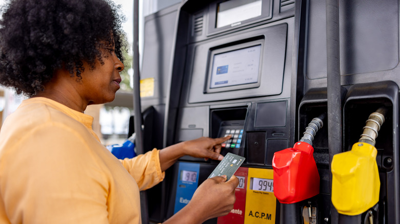 Woman paying for gas at pump with credit card
