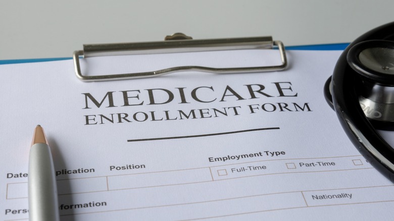 Medicare enrollment form on clip board with pen and stethoscope
