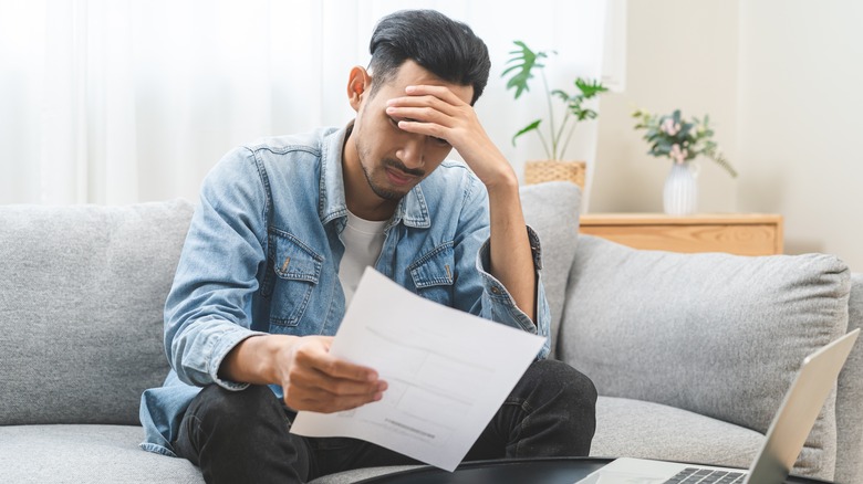 Young man struggling to pay bills on couch