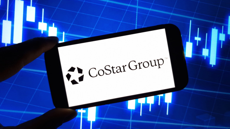 CoStar's logo on a phone screen with a blue candlestick chart in the background