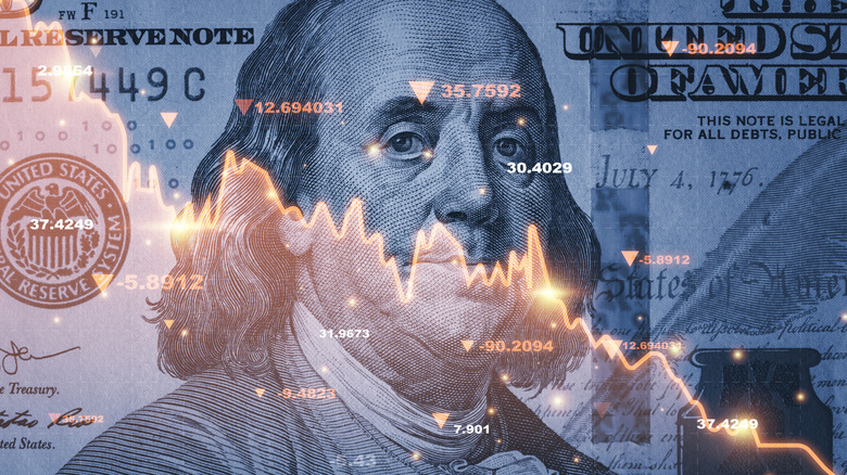 A transparent red price chart indicating falling stock prices layered over a $100 bill