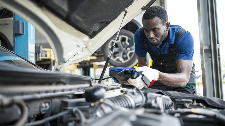 Auto mechanic running a test on a car under the hood