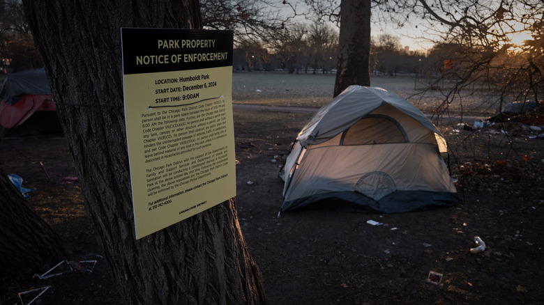 Enforcement sign in front of series of tents in early morning