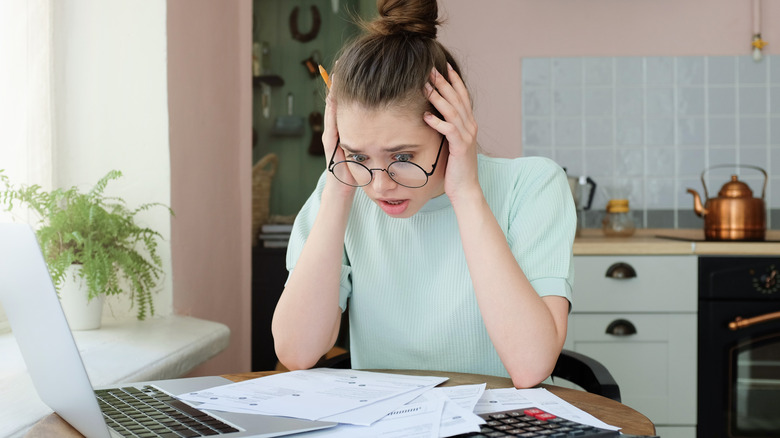 young woman in kitchen surprised by electricity bill