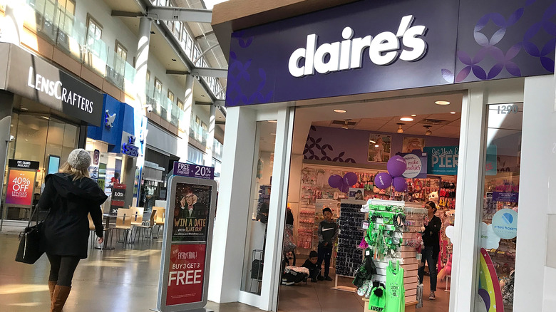 Image of Claire's mall store with woman in black walking by