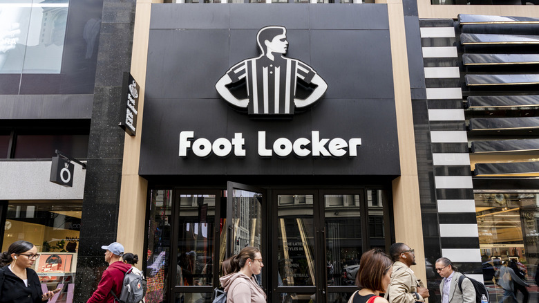 Several people walking in front of a Foot Locker store