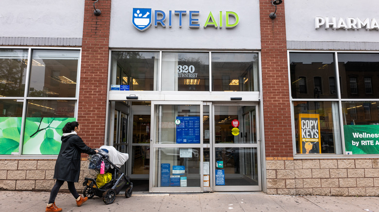 Woman pushing stroller entering Rite Aid store