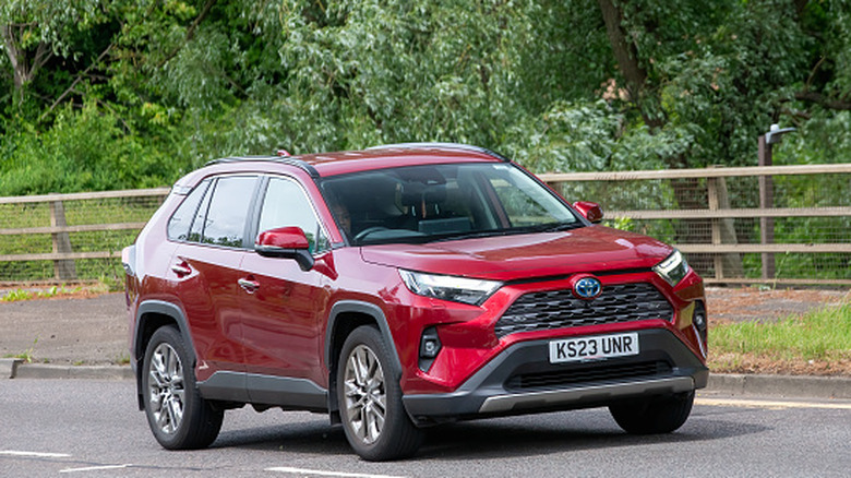 2023 red Toyota Rav4 hybrid electric car driving on a British road