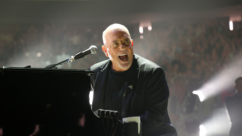 Billy Joel with performing on stage with an ecstatic expression