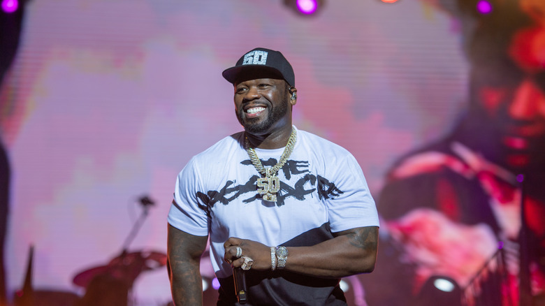 Curtis "50 Cent" Jackson smiling while performing on stage.