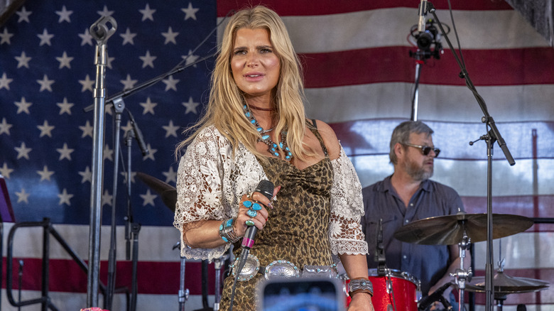 Jessica Simpson holding a microphone while performing on stage.