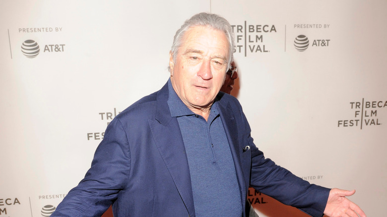 Robert DeNiro standing with arms open wide at the Tribeca Film Festival.